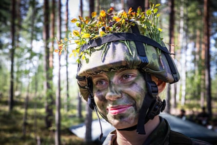 Emma with her face painted green wearing a military helmet decorated with flowers.