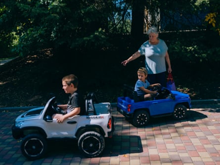 Valentyna with her grandsons driving small electric cars