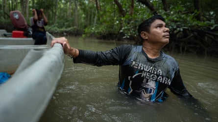 Man wading through water holding on to his boat