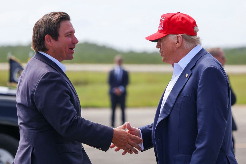 President Donald Trump shakes hands with Florida Governor Ron DeSantis at the Dade-Collier Training and Transition Airport on the day of the opening of a temporary migrant detention center informally known as 