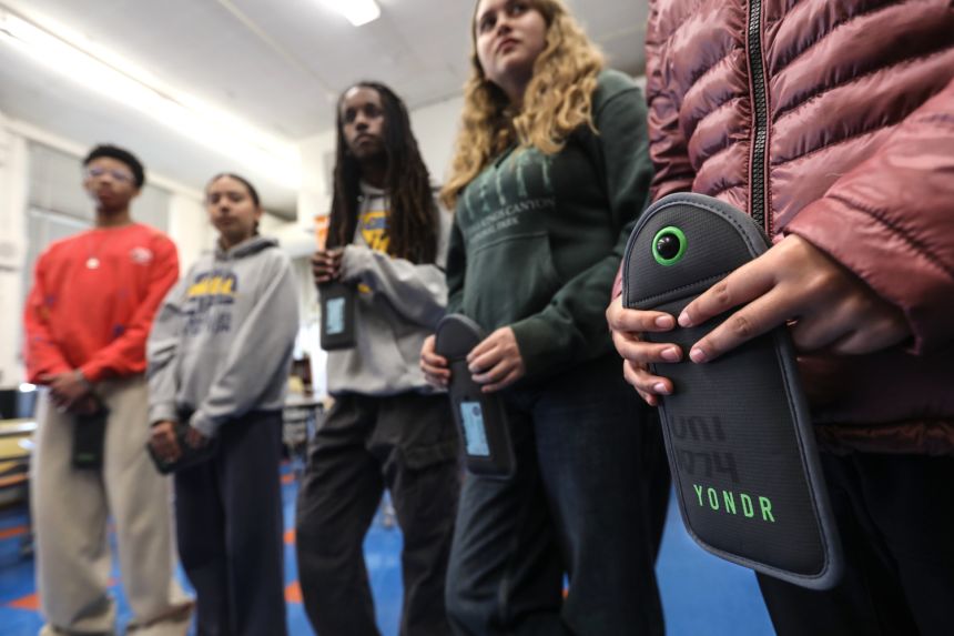 Students of University High School Charter in Los Angeles hold onto Yondr pouches that lock their smart phones inside during school hours.
