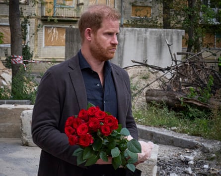 Prince Harry holding red roses in a yard