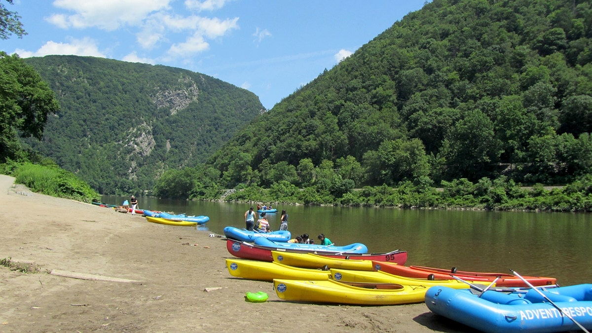 people standing near kayaks and canoes on shore of river