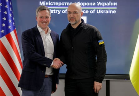 Denys Shmyhal shaking hands with Dan Driscoll in front of a ministry of defence sign