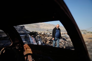 Mohammad Dalal looks at scorched cars in his scrapyard. The viewpoint is from inside a scorched car