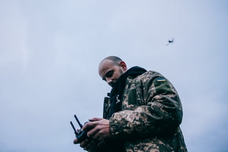 Maksym hold a controller, with a drone visible in the sky above him