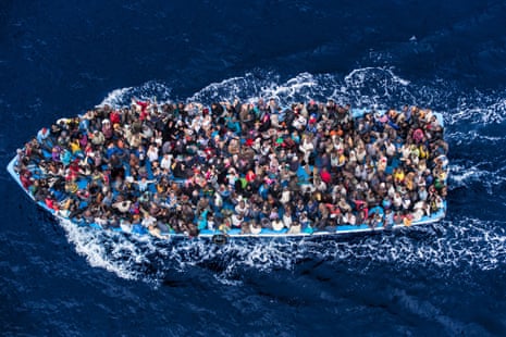 A boat crammed with African asylum seekers heading to Italy, photographed from above, against a deep blue sea, June 8 2014