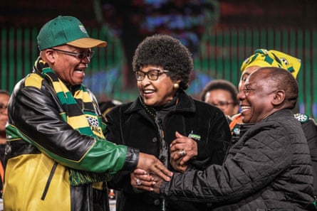 Jacob Zuma and Cyril Ramaphosa shake hands, with Winnie Mandela standing between them