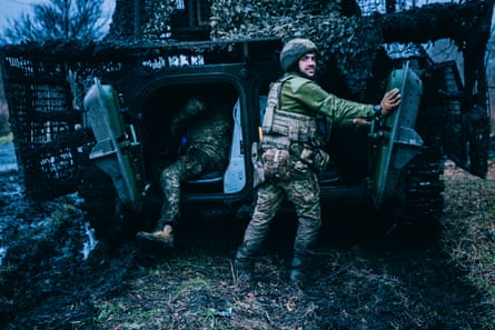 Soldiers next to a camouflaged armoured vehicle