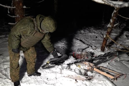 A man in camouflage standing by a downed drone