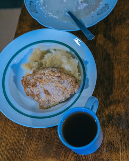 A mug of coffee next to a plate with an omelette and some mashed potatoes on it