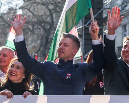 Péter Magyar holds aloft a Hungarian flag during a march.