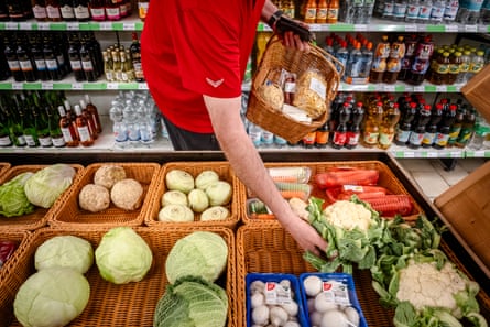 A person picking up a cauliflower from the vegetable stand.