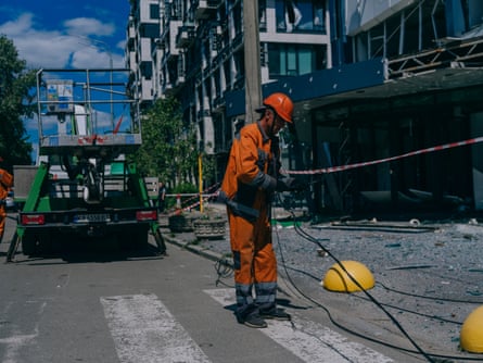A worker in a hard hat deals with a damaged electricity line on the street