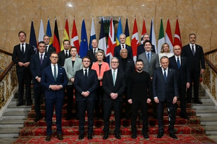 The nineteen leaders standing on some steps for a photo in front of their nations' flags