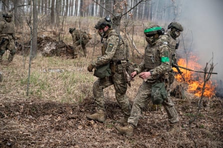 Soldiers in camouflage in a forest with burning grass