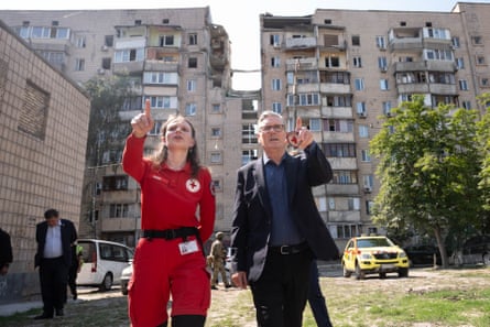 A woman in medical uniform and the British prime minister Keir Starmer point as they look at buildings damaged by Russian missile strikes.