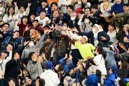 fans reach up to catch a baseball