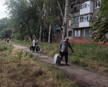 Civilians carry away their belongings during an evacuation of Druzhkivka.