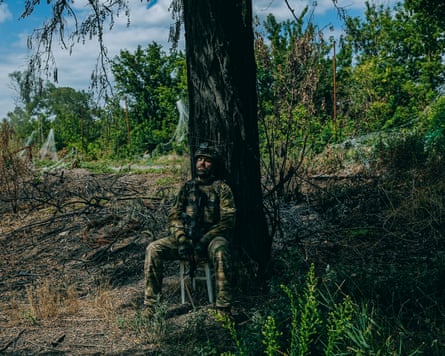 Young sitting down with his back leaning on a tree trunk.