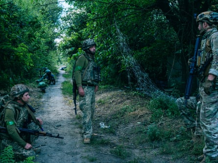Soldiers talking to each other under trees.