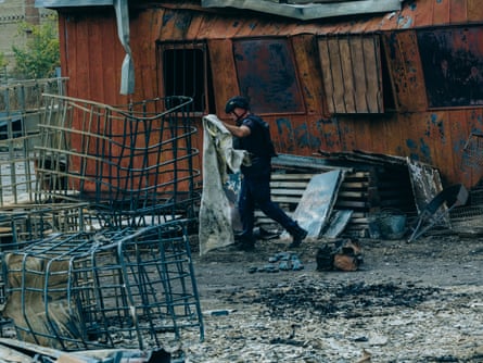 A rescue worker carrying a sheet surrounded by debris 