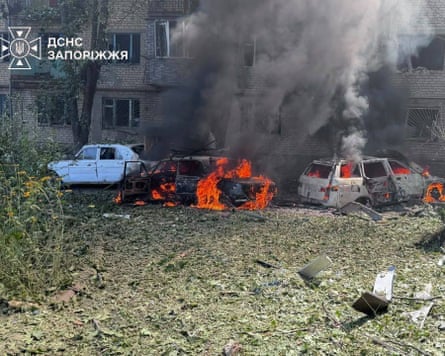 Emergency crews work at the scene where cars are burning following Russian airstrikes in Zaporizhzhia, Ukraine