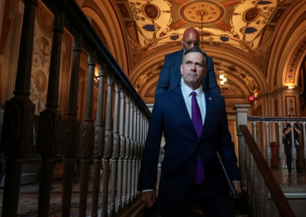 In a dark suit, light blue shirt and purple tie, CIA director John Ratcliffe walks down a staircase in a government building on Capitol Hill