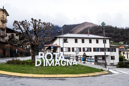 A large sign on a roundabout in a small town says ‘Rota d’Imagna’, with hills seen in the background