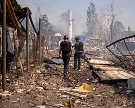 Police officers inspect the site of a missile or drone strike on a warehouse.
