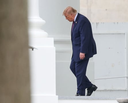 President Trump walks down steps at the White House, looking down