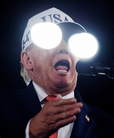Donald Trump shouts into a microphone, while bright lights reflecting off a protective screen obsure his face