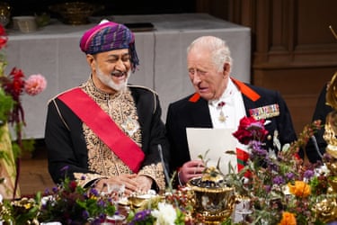King Charles and the sultan of Oman smile together at a flower-decorated state banquet table