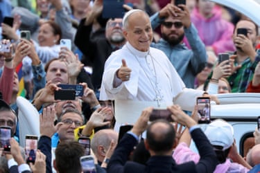 Pope Leo gives a thumbs up amid a cheering crowd, many with phones raised to take photos