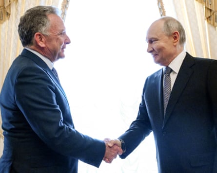 Vladimir Putin shakes hands with Steve Witkoff in front of tall curtained windows