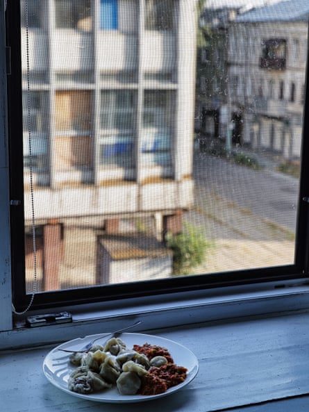 A plate of food on a windowsill with a view of a street beyond.