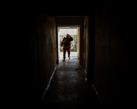 Silhouette of a paramedic standing in a door to the street at the end of a passageway.
