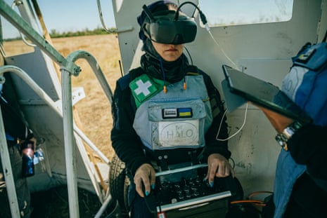 A deminer wearing VR goggles working behind a protective shield.