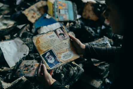 A person hold’s the remains of a picturebook with the charred remains of other children’s books on the floor