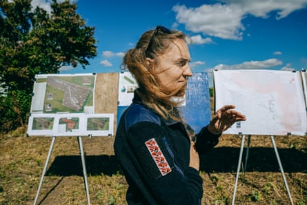 Valeriia Shumska stands near boards with maps and other information in a field.