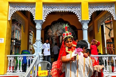 A devotee carries Adrija Banerjee, dressed as  the goddess Kumari, toward a temple
