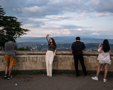 A woman takes a selfie overlooking Tbilisi from Mtatsminda Park.