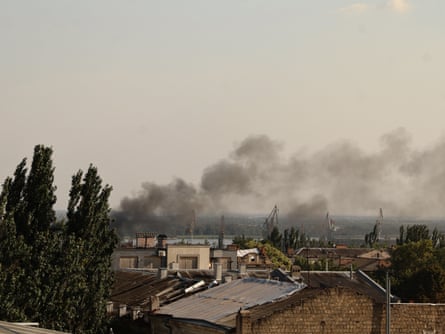 A view over rooftops with black smoke above them. 