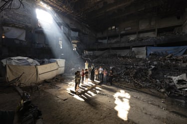 A sunbeam illuminates children inside a damaged, rubble-filled building
