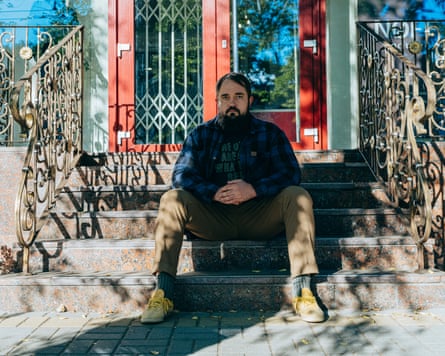 Artem Sova sits on the steps to a building