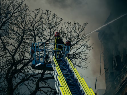 Firefighter up a ladder spraying water with hose