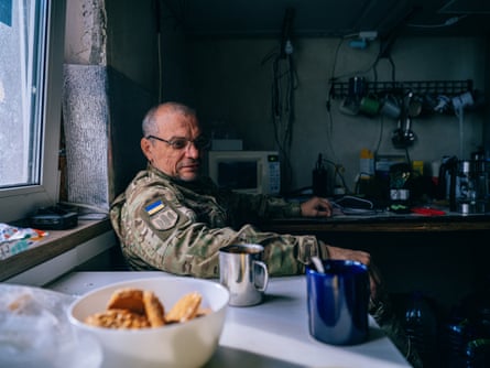 Sensei sat at a kitchen break table with a hot drink in a mug beside him