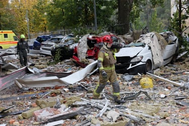 Emergency workers walk through debris and smashed-up cars after a drone strike