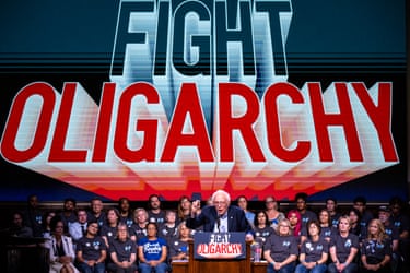Bernie Sanders speaks at a podium before seated supporters and under a large ‘Fight Oligarchy’ sign